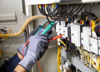 Electrician engineer tests electrical installations and wires on relay protection system. Adjustment of scheme of automation and control of electrical equipment.